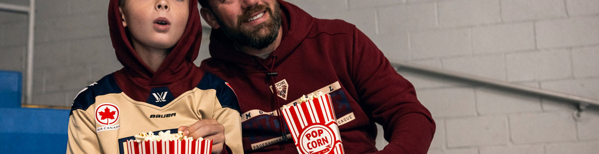 Father and son wearing Bauer Montréal Victoire Hoodies cheering in the stands.