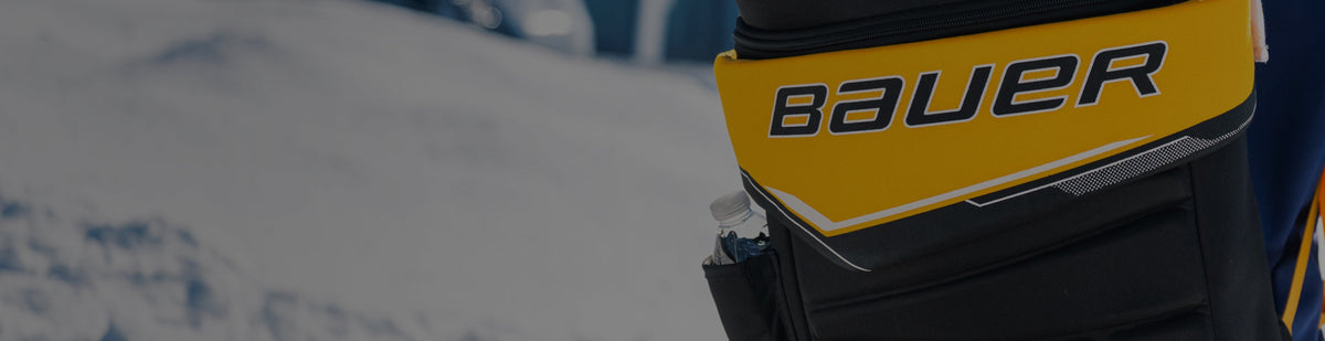 Boy standing outside wearing a BAUER GLOVE BACKPACK - 17L, winter apparel and holding a hockey stick