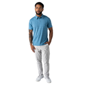 Man wearing a blue patterned polo shirt and white pants on a white background