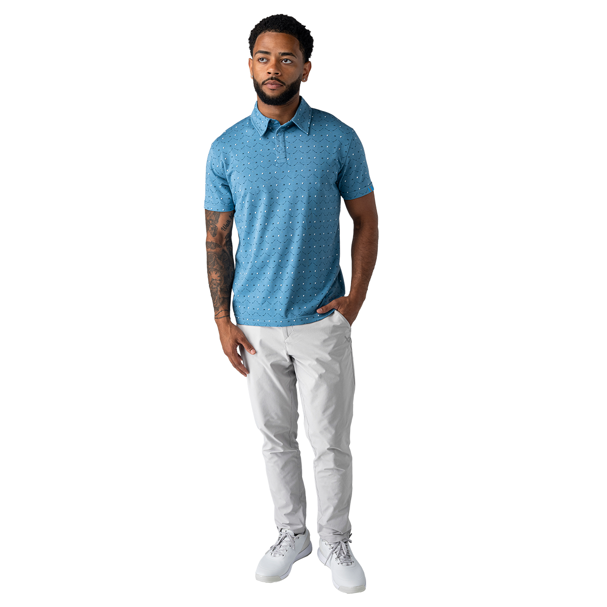 Man wearing a blue patterned polo shirt and white pants on a white background