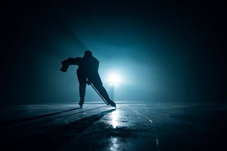 hockey player silhouetted on an ice rink with moody lighting